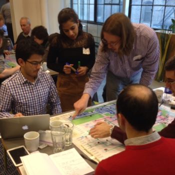 Participants gathered around a map, pointing at it, debating the design of routes.